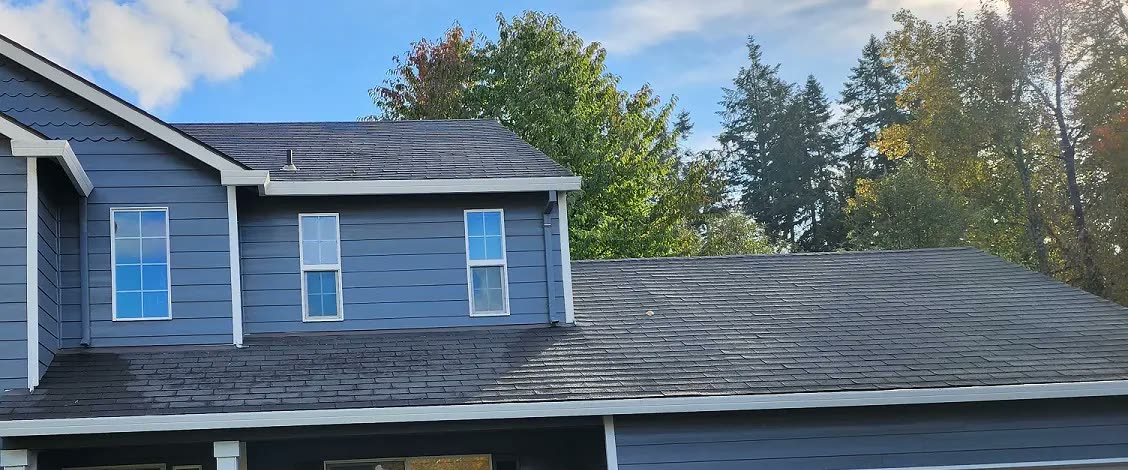 A finished roof and clean gutter line on a two-storey Salem house, photographed from the driveway
