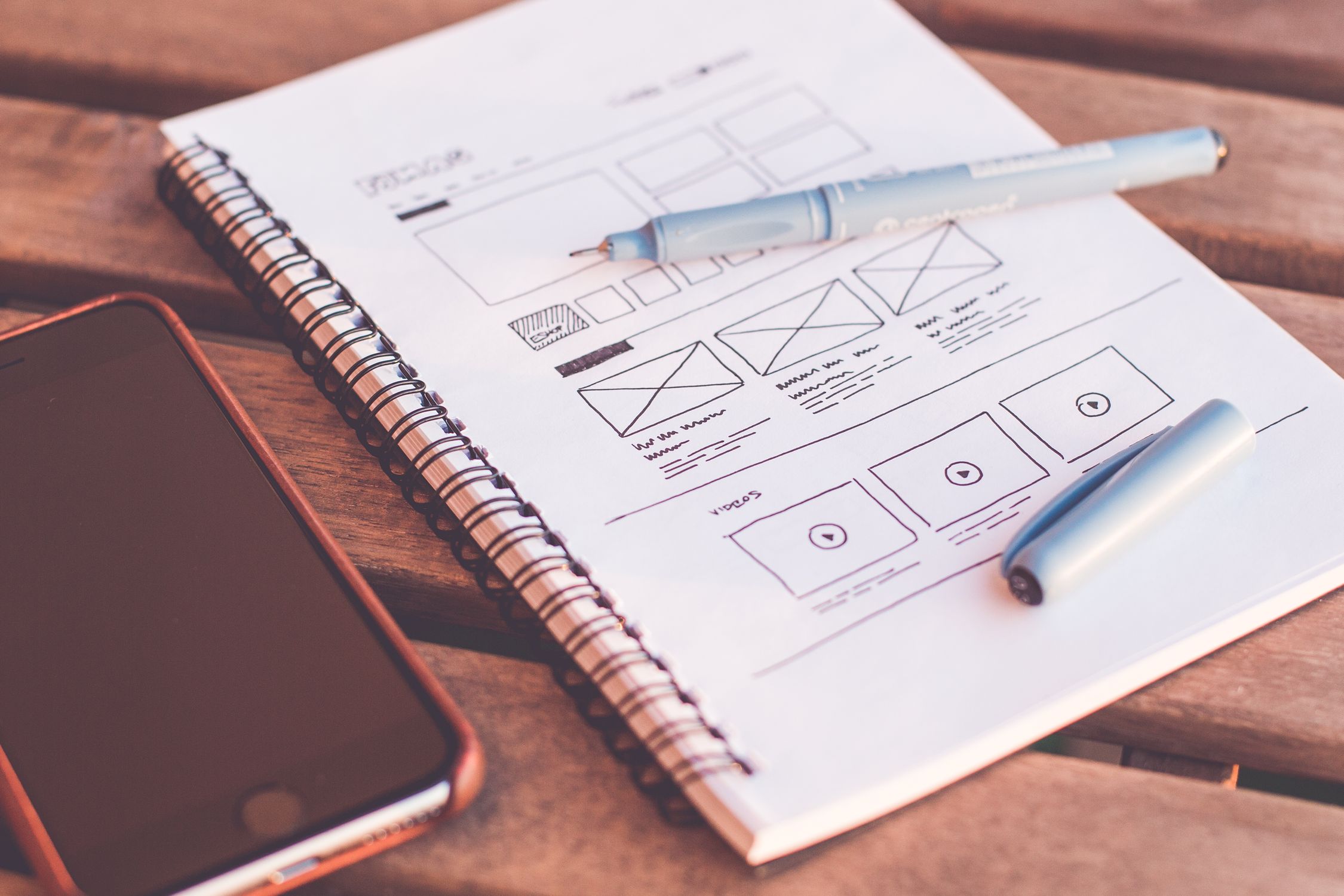 Developer sketching wireframes on paper next to a laptop